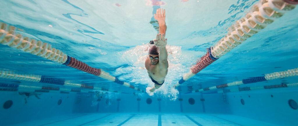 Swimmer performing butterfly stroke underwater in a swimming pool lane with lane dividers